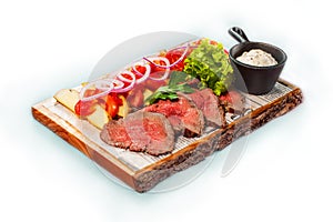 Beef with potatoes and greens on a wooden tray.