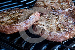 Beef qua burgers begin to cook on the gas barbecue