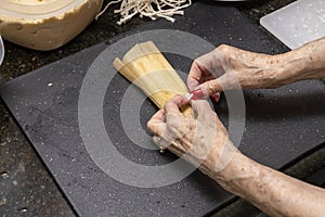 Beef red chili Tamales being made assembled by hand on a kitchen counter top
