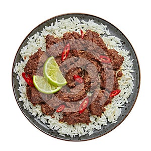 Beef Rendang on black plate isolated on white. Indonesian padang cuisine meat dish. Asian food. Top view