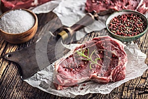 Beef Rib Eye steak with salt pepper and rosemary on wooden table