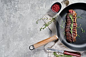 Beef rump steak roasted rear in pan. Grey background, top view.