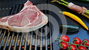 Beef steak with bone on cast iron grill barbecue, vegetables asparagus with bacon. Top view