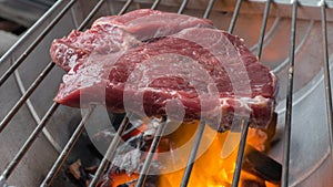 Beef steak cooking over flaming grill