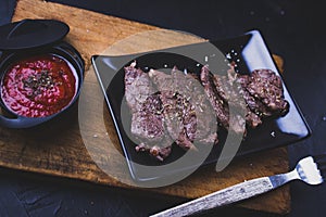 Beef steak cut into strips with tomato sauce on wood photo