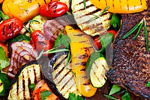 Beef steak and Grilled vegetables. On cutting dark board background