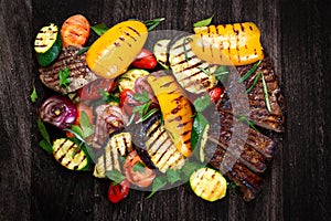 Beef steak and Grilled vegetables. On cutting dark board background