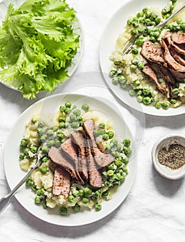 Beef steak with mashed potatoes and creamy green peas sauce on light background, top view