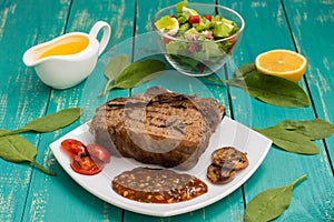 Beef steak medium rare on the grill with barbecue sauce. wood background