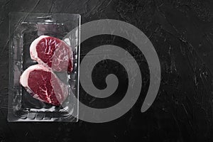 Beef steak pack, on black dark stone table background, top view flat lay, with copy space for text