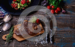 Beef steak. Piece of Grilled BBQ beef marinated in spices and herbs on a rustic wooden board over rough wooden desk with a copy sp