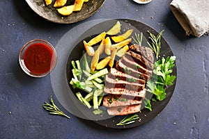 Beef steak with potato wedges and cucumber salad