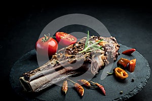 Beef steak with rosemary, chili peeper and tomatoes on slate board