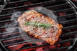 Beef Steak with sea salt, spices and rosemary roasts at grill. Smoking Beef Steak at grill