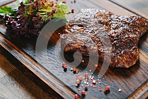 Beef steak served on wooden board plate, grilled fried meat with grill.