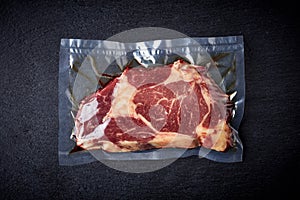 Beef steak vacuum sealed on black background, from above