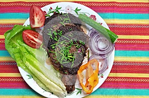 Beef steak on a white plate. Entrecote. Rib-eye. Coarsely chopped fresh vegetables as side dish