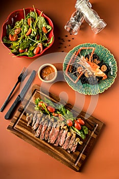 Beef steak on a wooden background. Sliced grilled meat barbecue steak Strip loin with knife and fork carving set on wooden Cutting