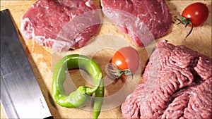 Beef steaks, ground meat on cutting board and counter top.