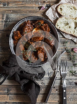 Beef stew in a frying pan on a wooden rustic table.