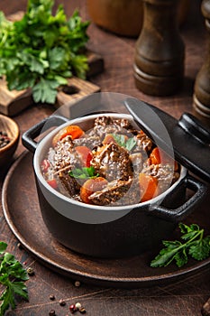 Carne guisada verduras en negro maceta sobre el oscuro de madera 