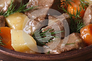 Beef stew with vegetables and dill in a pot macro.
