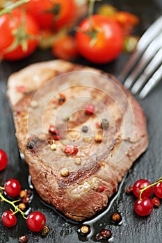 Beef on a stone with berries and tomatoes