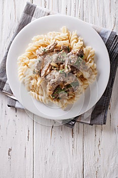 Beef stroganoff with pasta fusilli . Vertical top view