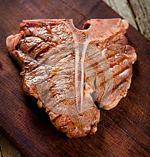 Beef T-bone steaks on dark old wooden board