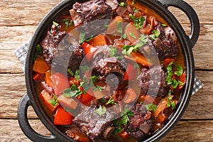 Beef tail oxtail stew cooked in traditional spanish food rabo de toro closeup on a pot on the table. Horizontal top view