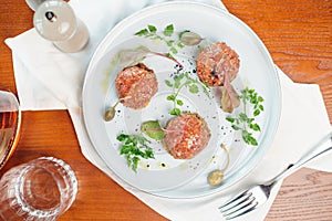 Beef tartar with an egg on a stone plate. Cherry tomatoes. Rosemary. Spice.