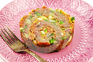 Beef Tartare cold appetizer of raw minced meat with egg yolk, spices, onions, olive oil, lemon juice