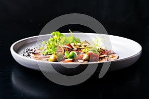 Beef tongue with sauce and vegetables on a white plate