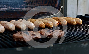 Beefburgers and sausages cooking on an open grill