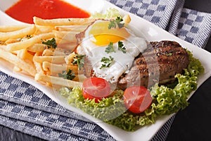 Beefsteak with fried egg and fries on a plate closeup. horizonta