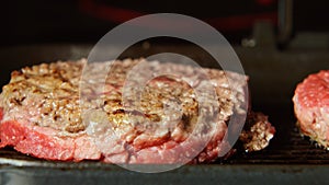 Beefsteaks frying on a grill - front view