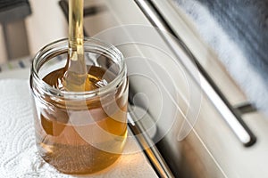 Beekeeper filling up the fresh golden new honey into glass jars