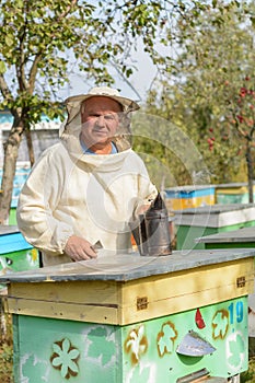 Beekeeper hives in the apiary near blows smoker for bees.