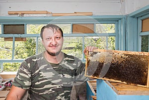 Beekeeper holding in hands Bee honeycombs of wax in a wooden frame.