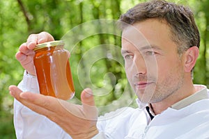 Beekeeper holding jar honey