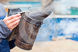 Beekeeper holds a chimney in his hand for fumigation of bees_