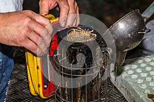 The beekeeper prepares a smoker