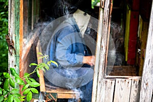 Beekeper sitting in old smoky beehive and checks bee work