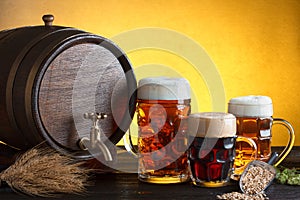 Beer barrel with beer glasses on wooden table with wheat bunch and hop
