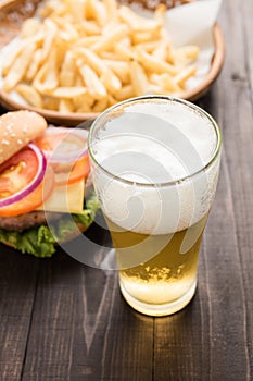 Beer being poured into glass with gourmet hamburgers and french
