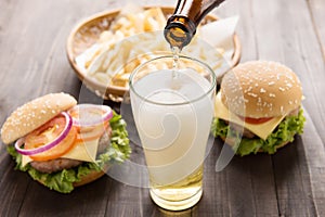 Beer being poured into glass with gourmet hamburgers and french