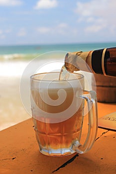 Beer being poured into a glass on an idyllic beach