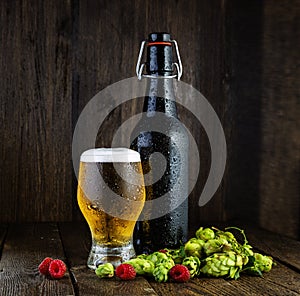 Beer bottle and beer glass with raspberries and hops