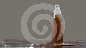 Beer bottle with openned bottlecap, foam split out on table