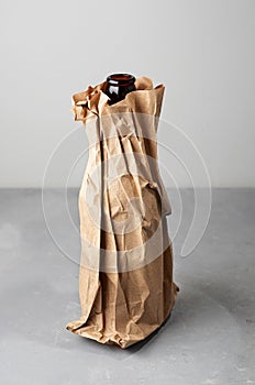 Beer bottle in the paper bag on gray concrete background